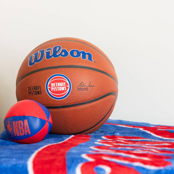 Pistons Alliance Full Size Basketball on top of Blanket next to Plush Basketball