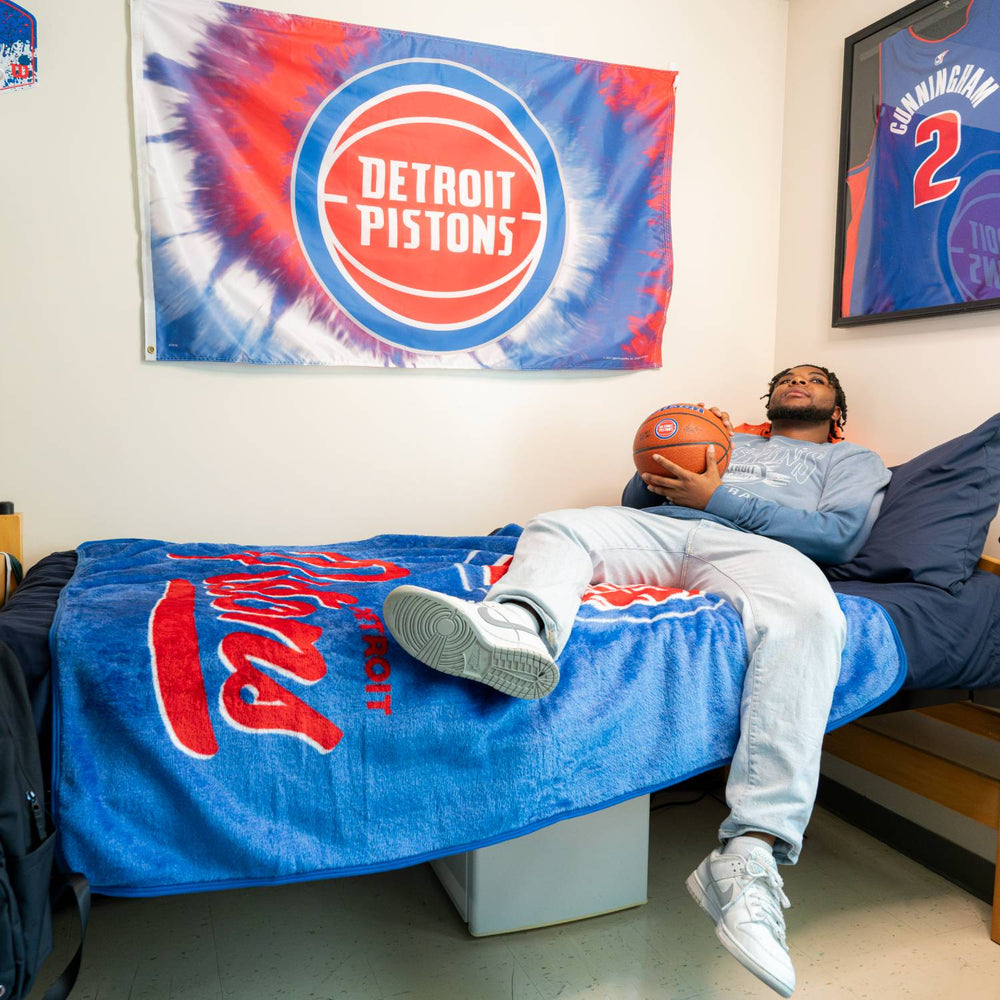 Student Lounging on Detroit Pistons Signature Raschel Plush Throw - In Blue