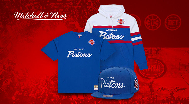 Mitchell & Ness Detroit Pistons sports gear including a jacket, t-shirt, and cap on a red background.