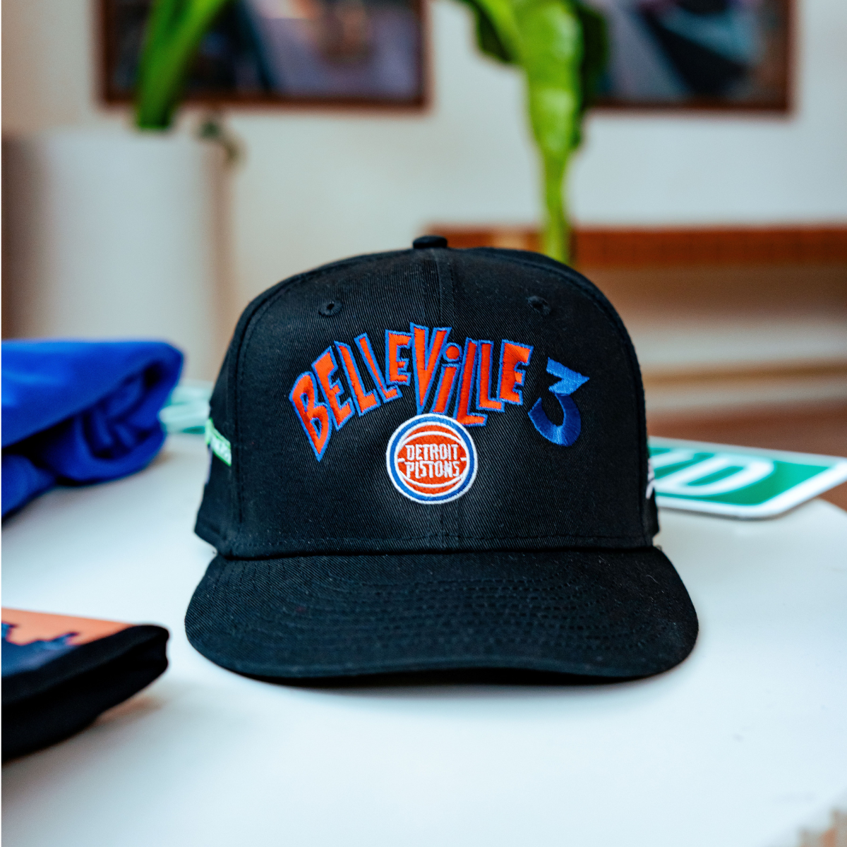 Black cap with 'Belleville' and 'Detroit Pistons' text on a table