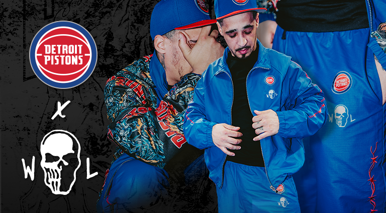 Person wearing a blue jacket with Detroit Pistons logo, surrounded by dark background with Pistons branding.