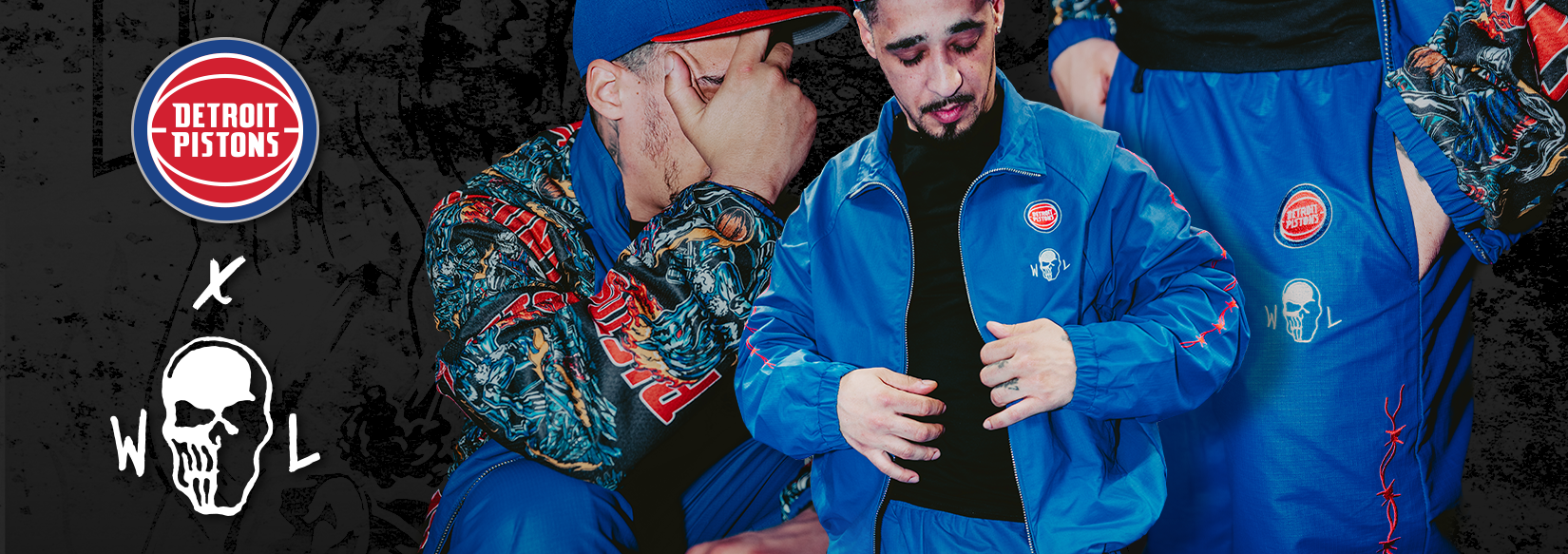 Two people wearing matching blue jackets with logos, one with a Detroit Pistons logo, on a dark background.