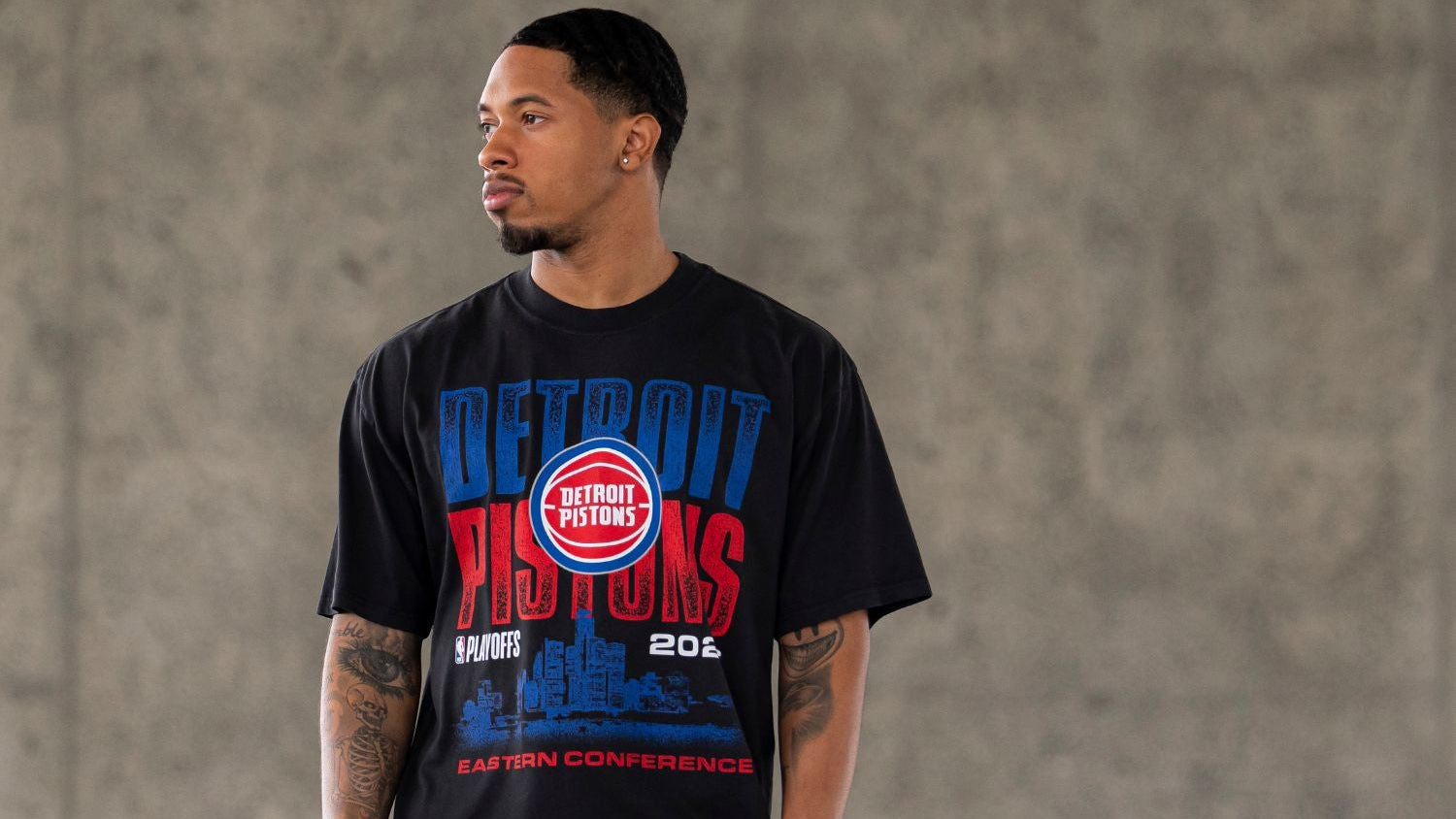Man wearing a Detroit Pistons t-shirt against a gray background